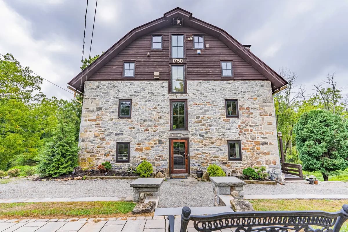 Front facade of the stone mill with its gambrel roof, seen across the lawn