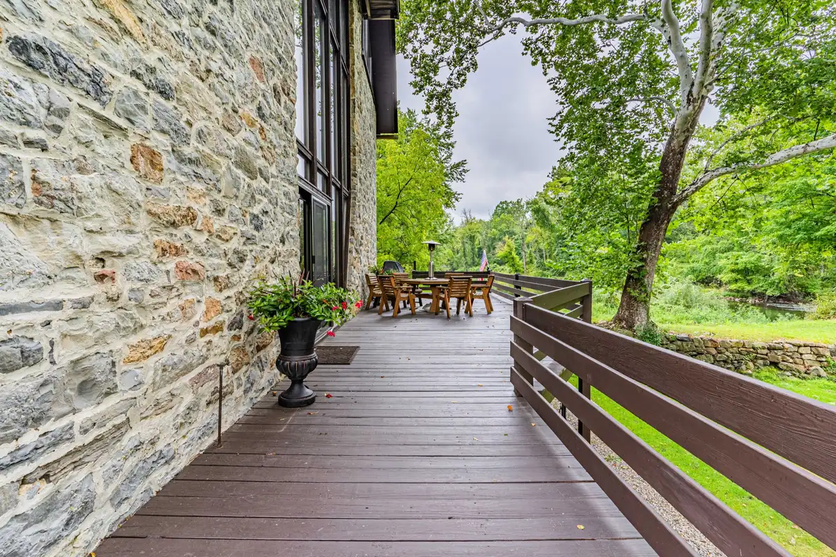 Wraparound deck along the original stone wall with potted flowers